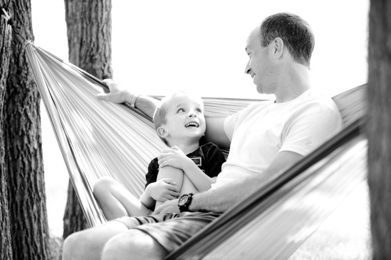 Father and son talking outside in a hammock